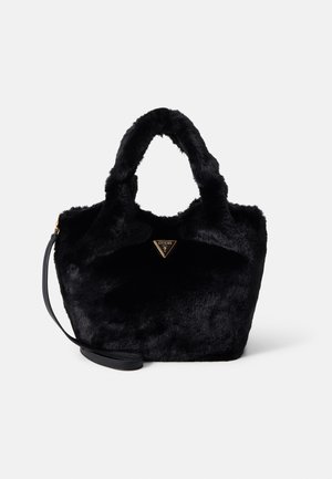 Czarna torebka z futerkiem ekologicznbym, z krótkimi uchwytami, odpinanym paskiem na ramię oraz złotym trójkątnym logo Guess na środku przedniej strony.