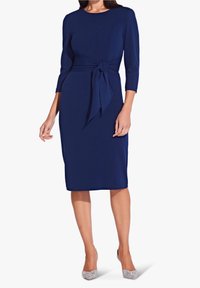 Laivansinis, polvipituinen mekko, jossa on kolme neljännesosaa hihat, solmittu vyötäröyksityiskohta, sileä pinta ja siluetti, joka korostaa vartaloa.