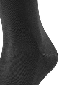 Calza nera realizzata in tessuto liscio con una texture a coste. Caratterizzata da un tallone sagomato e una punta rinforzata per una maggiore durabilità.