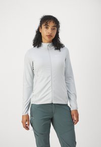 Lichtgrijze zip-up jack gemaakt van soepel, rekbaar materiaal, met lange mouwen en zijzakken, gecombineerd met donkergroene broek.