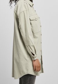 Ljusgrön kordflorsskjorta med skjortkrage, knappstängning fram och två bröstfickor. Har långa ärmar med knappslut.