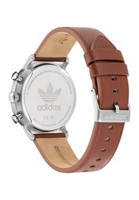 Hõbedane roostevabast terasest kell pruunist ehtsast nahast rihmaga. Omab krono nuppe, bränditud tagust ja poleeritud metallist lukku.