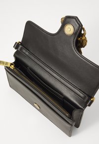 Black leather handbag with a zippered compartment, interior card slots, and a decorative gold-colored hardware accent.