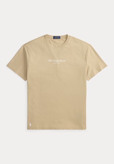 Μπεζ κοντομάνικη μπλούζα Polo Ralph Lauren με στρογγυλή λαιμόκοψη, λευκό τυπωμένο λογότυπο "Polo Ralph Lauren New York" στο στήθος και μικρό λογότυπο κοντά στο τελείωμα.