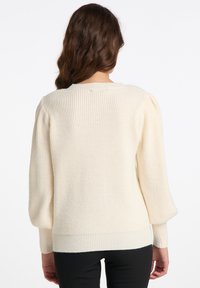 Pulover de tricot color crem, cu mâneci lungi și bufante, țesătură texturată și tiv cu coastă. Vedere din spate arată decolteu rotund și detalii de cusătură.