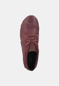 Chaussure en cuir rouge avec embout rond, couture décorative et lacets beiges. L'intérieur porte le nom de la marque "Josef Seibel." Texture lisse.