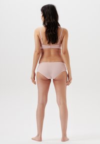 Lichtroze bralette en bijpassende boyshorts van gladde stof, met verstelbare bandjes en een eenvoudig, naadloos ontwerp.