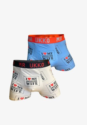 Bermudashorts in Blau und Weiß mit dem Text "Ich ❤️ MEINE TOLLE FRAU". Die blaue Variante hat einen roten Bund; die weiße Variante hat einen schwarzen Bund. Aus Baumwolle.