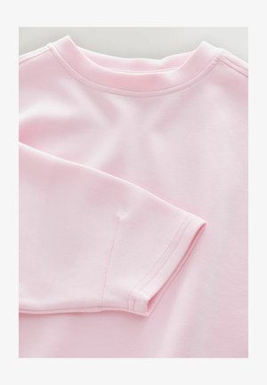 Svetlo roza pulover z okroglim izrezom, dolgimi rokavi in gladko teksturo z vidnimi šivi.