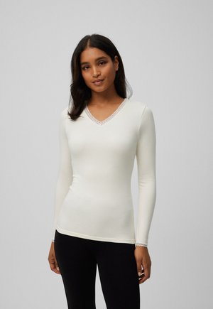 Blusa de manga larga en color blanco roto con escote en V y ribetes de encaje en el cuello, diseñada con una silueta ajustada y una textura suave.