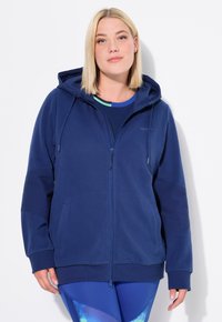 Felpa con zip blu navy, con cappuccio, polsini a costine e tasche laterali. Tessuto morbido con una texture liscia, progettata per comfort e facilità di movimento.