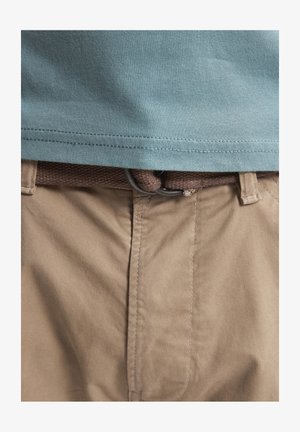 Lichtblauwe katoenen T-shirt met korte mouwen, gecombineerd met tan chino's met een bruine geweven riem en een zilveren lusgesp.