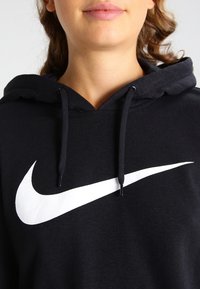 Černá mikina s kapucí a bílým logem Nike. Obsahuje stahovací kapuci, měkkou texturu a volný střih. Design zdůrazňuje atletický styl.