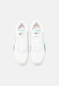 Ζευγάρι λευκά δερμάτινα αθλητικά παπούτσια Reebok με πράσινες λεπτομέρειες και λευκά κορδόνια, σε άποψη από πάνω σε λευκό φόντο.