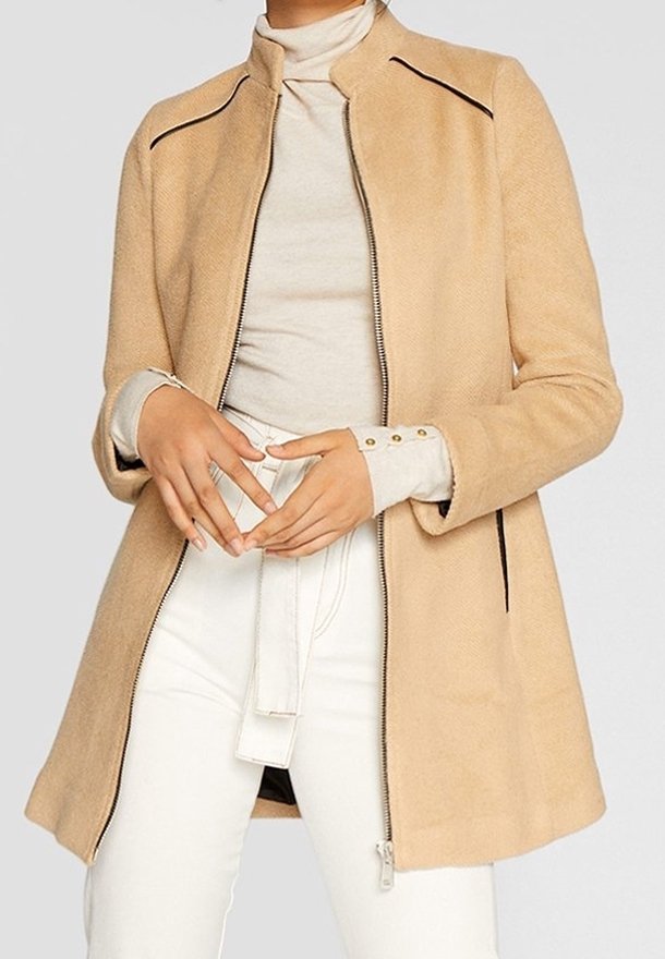Beige wool blend coat with a high collar, zip closure, and contrast piping. Features an A-line shape and two side zip pockets.