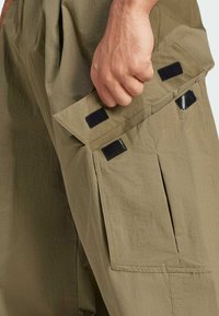 Cargo bukser i olivengrøn med lappe lommer, sorte Velcro-detaljer og et let, tekstureret stof for holdbarhed.