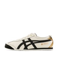 White leather sneakers with black accents, featuring a textured black toe cap and gold branding on the heel, lightweight with a slim profile.
