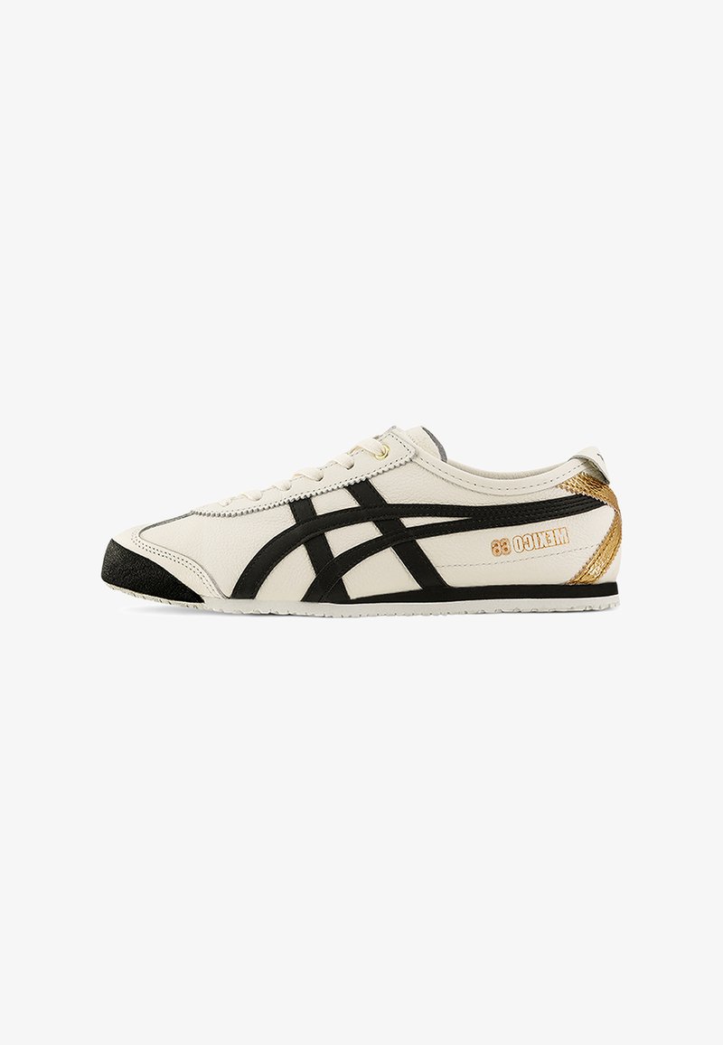 White leather sneakers with black accents, featuring a textured black toe cap and gold branding on the heel, lightweight with a slim profile.