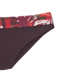 Bikiniunderdel i mörk lila med blommönstrad midjeband i rött, grönt och vitt; har en liten guldlogga och slät yta.