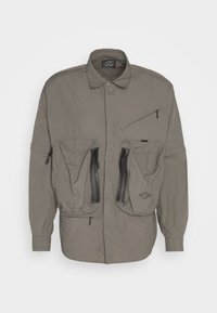 Light gray outdoor jacket with a collared neck, large front pockets, and zippered closures. Features a textured, lightweight fabric.
