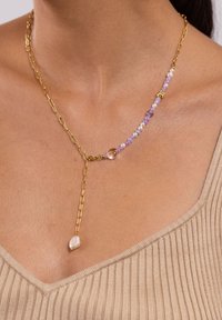 Goldene Ketten-Halskette mit lila und weißen Perlen, einer zentralen klaren Perle und einem hängenden Perlenakzent. Verstellbare Länge mit modernem Design.