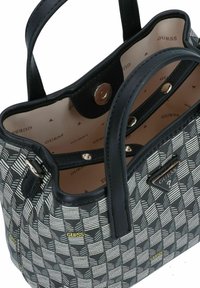 Sac à main noir et blanc à motif avec une forme structurée, deux poignées noires et des accents en métal doré à l'intérieur. Doublé d'un intérieur à logo beige.