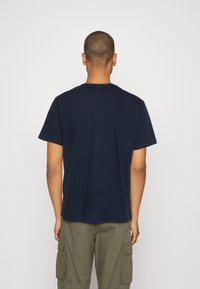 T-shirt en coton bleu marine avec un col rond classique et des manches courtes, offrant une coupe décontractée et sans graphismes ni logos visibles.