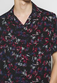 Schwarzes Kurzarmhemd mit einem bunten Palmenblattmuster in Rot, Weiß und Blau; verfügt über einen lässigen Kragen und eine vordere Knopfleiste.