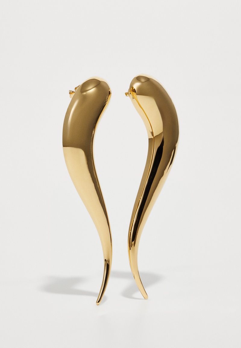Náušnice v zlatej farbe s elegantným, zakriveným dizajnom. Hladký povrch a predĺžený tvar, s dochádzajúcim koncom a bezpečným zapínaním na zadu.
