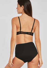 Melnā krūštura un augsto vidukļa apakšveļas komplekts. Krūšturim ir regulējamas siksnas un aizmugurējā aizdare ar acu un āķi. Audums ir gluds un elastīgs.