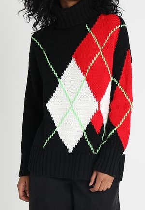 Jersey de cuello alto negro con grandes patrones de diamante argyle en rojo, blanco y verde, llevado por una persona con cabello rizado oscuro.