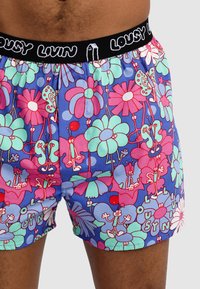 Colorful boxers made from soft fabric, featuring a vibrant floral and cartoon-like design in pink, green, and blue, with a black elastic waistband.