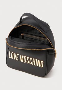 Schwarzer Rucksack aus glattem Material mit abgerundeter Form. Verfügt über goldene "LOVE MOSCHINO"-Buchstaben und eine innenliegende Tasche mit Reißverschluss.