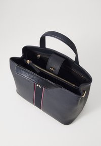 Borsa a tracolla in pelle texturizzata di colore blu navy con doppie zip. Presenta accessori dorati e strisce verticali rosse e bianche sulla parte anteriore.