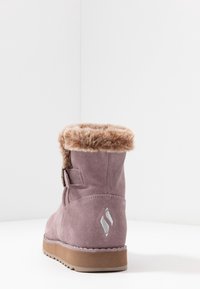 Fialové semišové kotníkové boty s umělou kožešinou na manžetě, bočním sponou a texturovanou gumovou podrážkou. Na zadní straně se nachází světle šedé embosované logo.