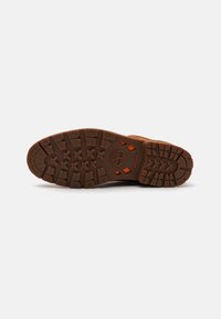 Semelle marron avec un motif de semelle robuste. Détails orange ; logo embossé au talon. Matériau en caoutchouc durable pour une meilleure adhérence.