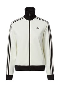 Chaqueta blanca con cremallera y cuello alto, detalles en negro y tres rayas negras en cada manga. Presenta un pequeño logo negro en el pecho.