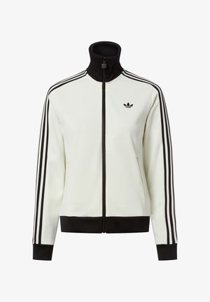 Bijela jakna na patent s visokim ovratnikom, crnim detaljima i tri crne pruge na svakom rukavu. Na prsima se nalazi mali crni logotip.