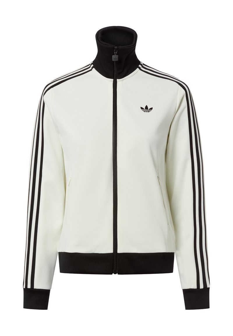 Chaqueta blanca con cremallera y cuello alto, detalles en negro y tres rayas negras en cada manga. Presenta un pequeño logo negro en el pecho.