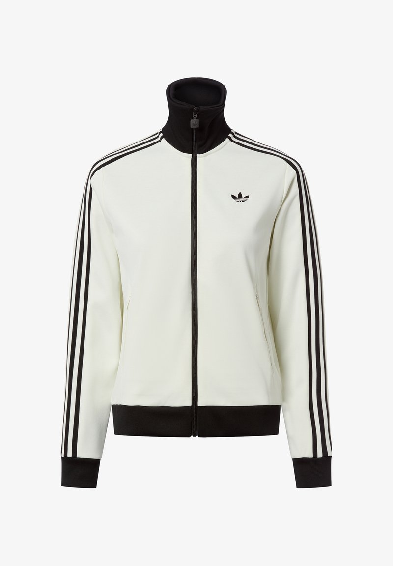 Chaqueta blanca con cremallera y cuello alto, detalles en negro y tres rayas negras en cada manga. Presenta un pequeño logo negro en el pecho.