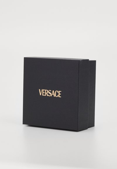 Black box with a textured surface, featuring a gold "VERSACE" logo on the front. Rigid rectangular design, simple and elegant.
