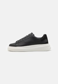 Schwarze Leder-Sneaker mit gummierter, weißer Sohle, abgerundetem Zehenbereich, sechs Ösen für die Schnürsenkel und dezentem Branding an der Seite.