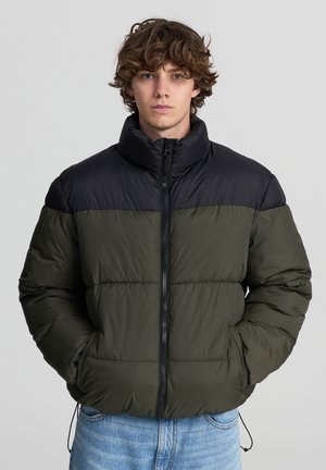 Giubbotto imbottito in verde oliva e nero, con colletto alto, chiusura con zip e tasche laterali; superficie liscia con dettaglio trapuntato.