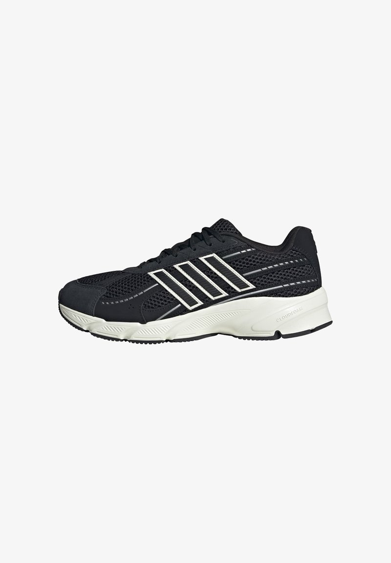 Chaussure de running noire en mesh avec semelle blanche et bandes diagonales blanches sur le côté, avec fermeture à lacets et talon rembourré.