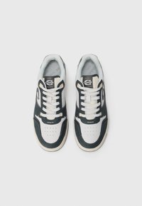 Schlanke Sneakers mit einem strukturierten Obermaterial in Schwarz und Weiß, beige Akzenten und einem klassischen Schnürdesign mit durchbrochenen Zehendetails.