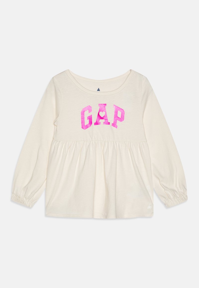 Long-sleeve cream top with gathered waist, featuring bold pink "GAP" graphic at the chest and elastic cuffs. Soft cotton material.