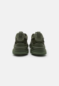 Zapatillas verdes de malla y goma con talón acolchado, tirador y suela gruesa. Incluyen paneles de ventilación y un ajuste ajustable.