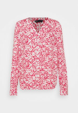 Blouse à manches longues avec motif floral rouge et blanc, col en V et petit bouton au col.