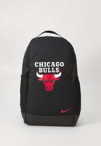 Crni ruksak od teksturirane tkanine s crvenim logotipom Chicago Bulls i bijelim natpisom. Uključuje bočnu mrežastu džep i Nike logotip.