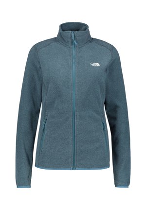 Dameblå fleecejakke med lynlås, stående krave og to lynlåslommer i siden, med The North Face-logo på venstre bryst.